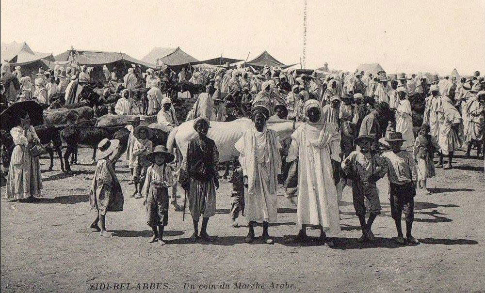 Foto akhir abad ke-19 dari pasar Beni Amer di Sidi Bel Abbes, Aljazair, memperlihatkan pedagang dan pengunjung berpakaian tradisional.